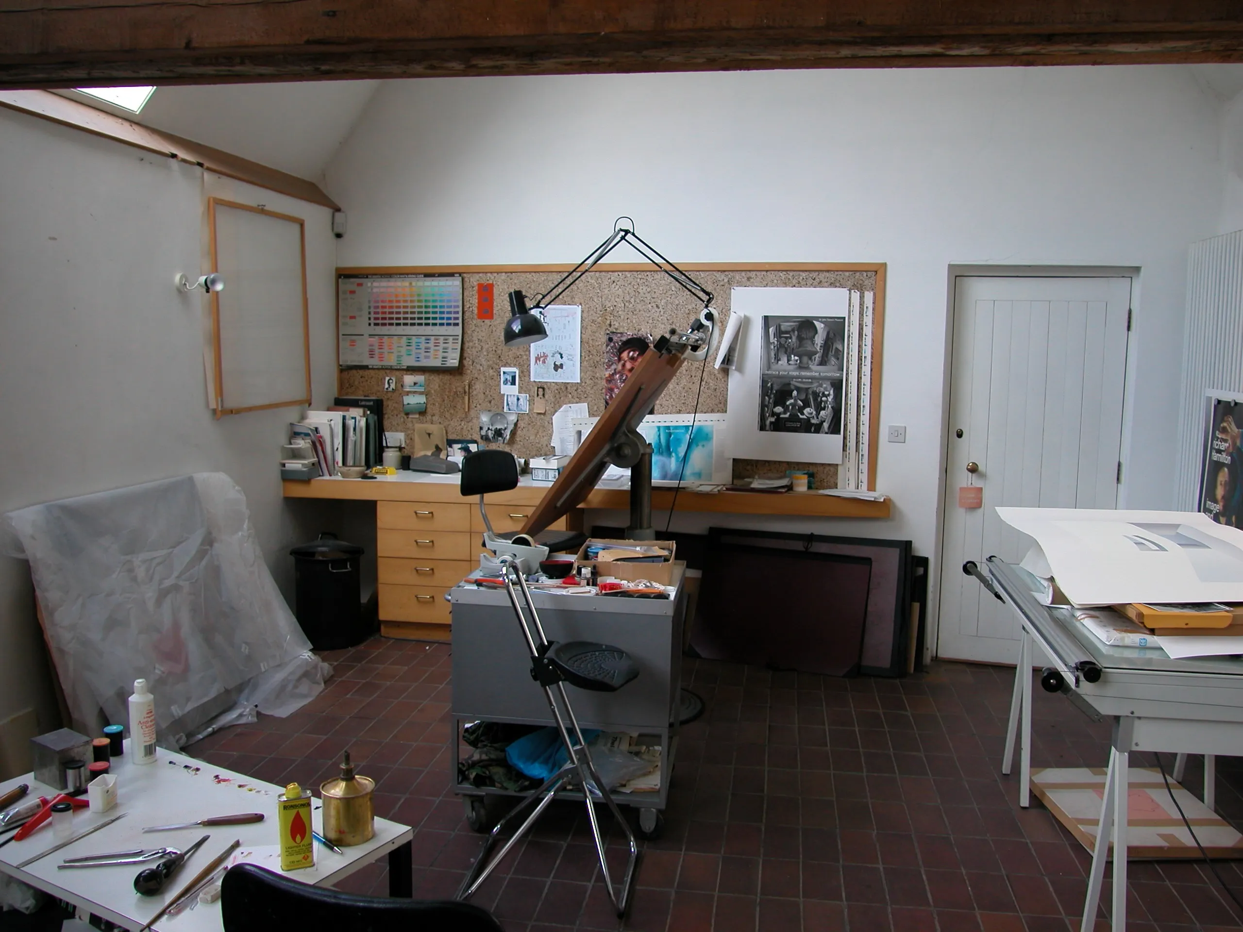 Richard Hamilton's studio: a tilted wooden drawing board and workbench with colour charts, prints and tools.